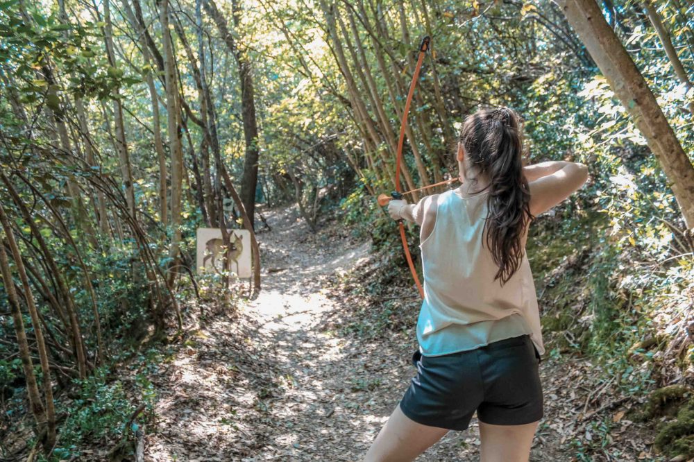une jeune fille qui tire à l'arc dans la forêt